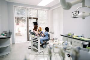 child with her mother in the dentists chair as the dentist answers the question do Dental Clinics Benefit from Offering CDCP Coverage