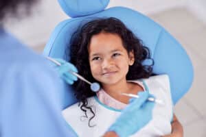 young girl smiling up at her dentist because she knows this is one of the main ways how to prevent cavities in children