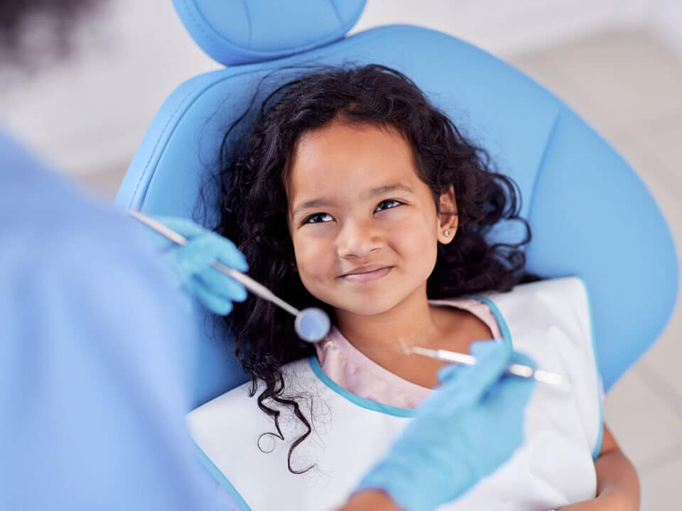 young girl smiling up at her dentist because she knows this is one of the main ways how to prevent cavities in children