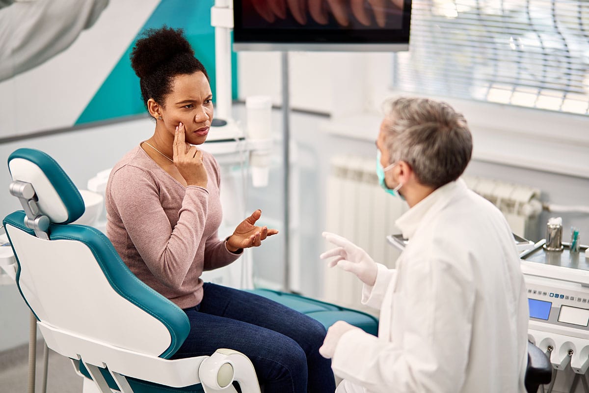 african woman is questioning her dentist about the safety and necessity for fluoride treatments