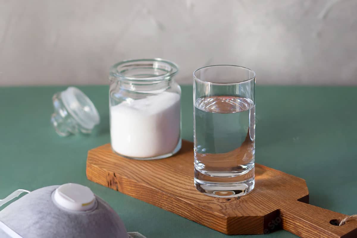 photo of a glass of water and a jar of salt ready to mixed and gargled with