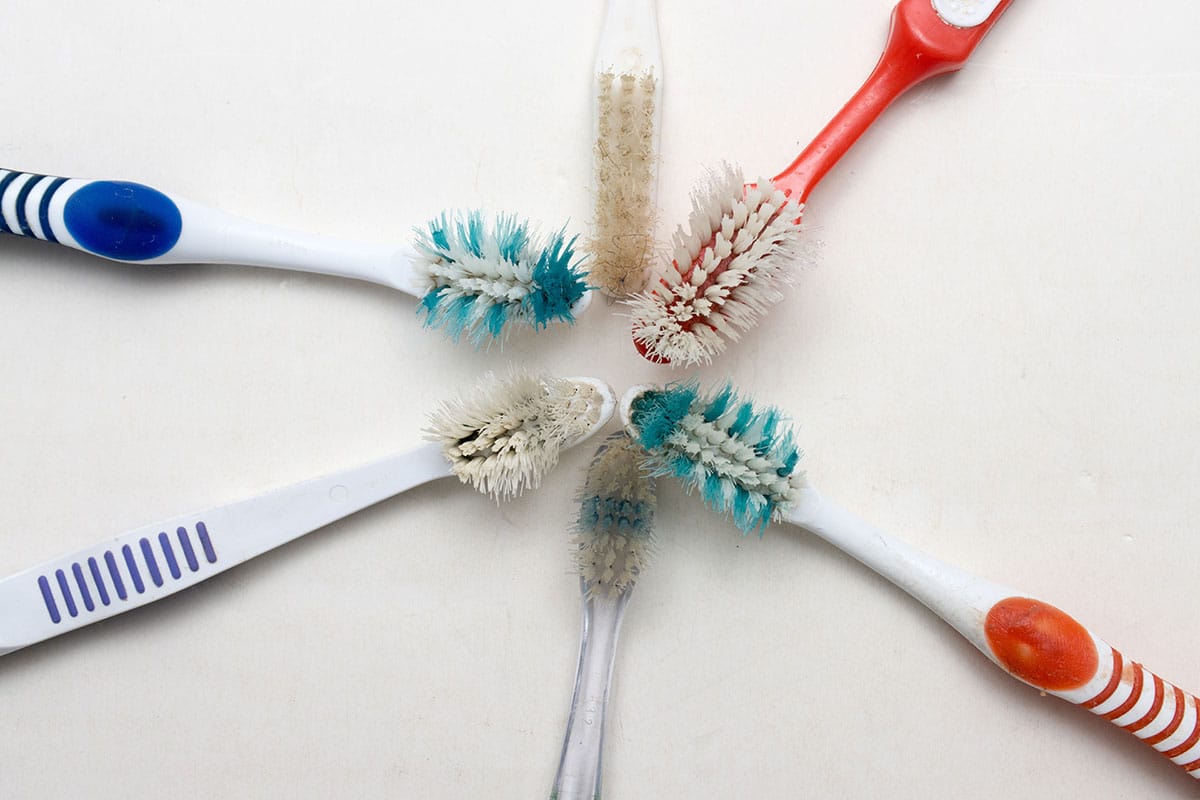 six frayed and dirty toothbrushes laid in a circle