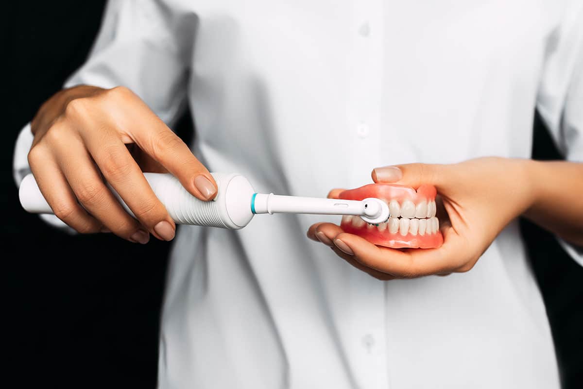 dentist shows how to use an electric toothbrush to help reduce gum damage from teeth brushing