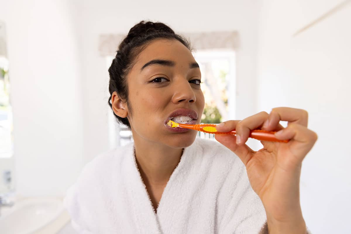 woman close up in the mirror brushing her teeth