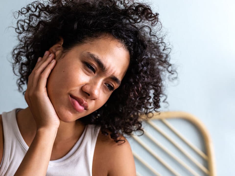 woman holding the side of her neck and head while wondering "can dental issues cause migraines and headaches?"