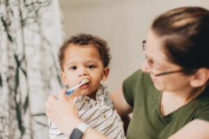 mom in the bathroom with her toddler putting our suggestions on how to motivate her toddler to brush their teeth to good use