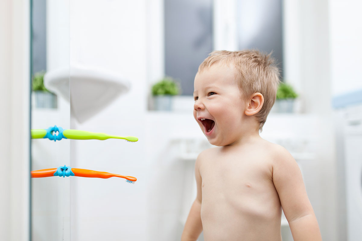 young toddler in the bathroom looking super motivated to brush his teeth