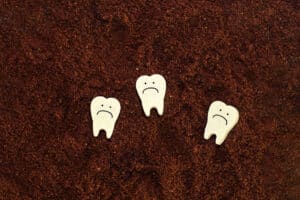 3 wood cutout teeth with frowns drawn on them signifying dental erosion causes and prevention