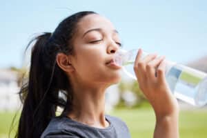 young woman drinking from a bottle of water as one of the many dry mouth solutions and treatments options