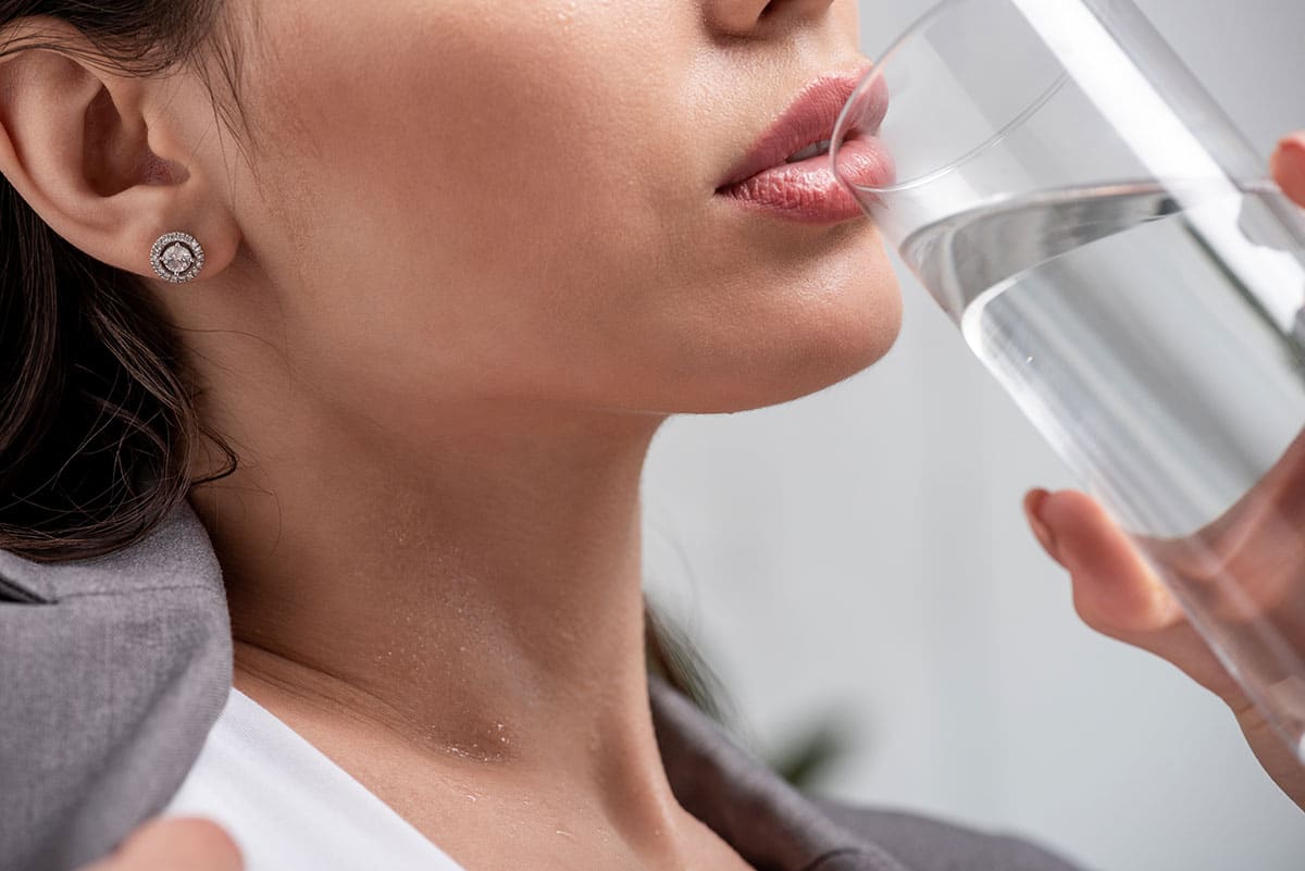 woman drinking froma glass of water as a home remedy for dry mouth