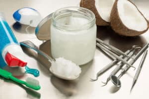 header image showing half a coconut one the left and a bottle of mouthwash on the right to show the question of does oil pulling promote better dental health