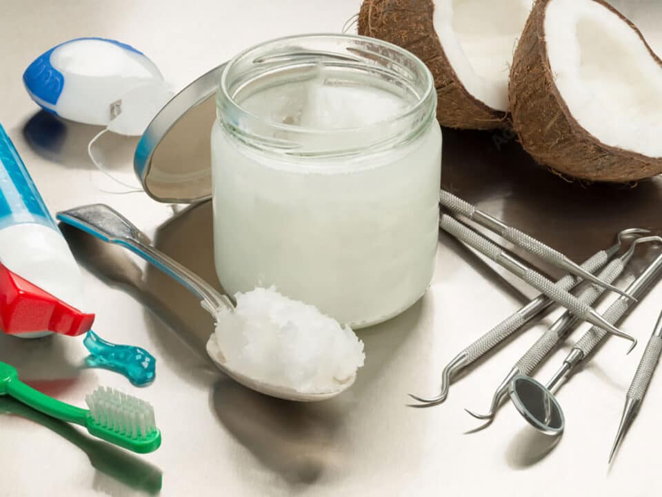 header image showing half a coconut one the left and a bottle of mouthwash on the right to show the question of does oil pulling promote better dental health