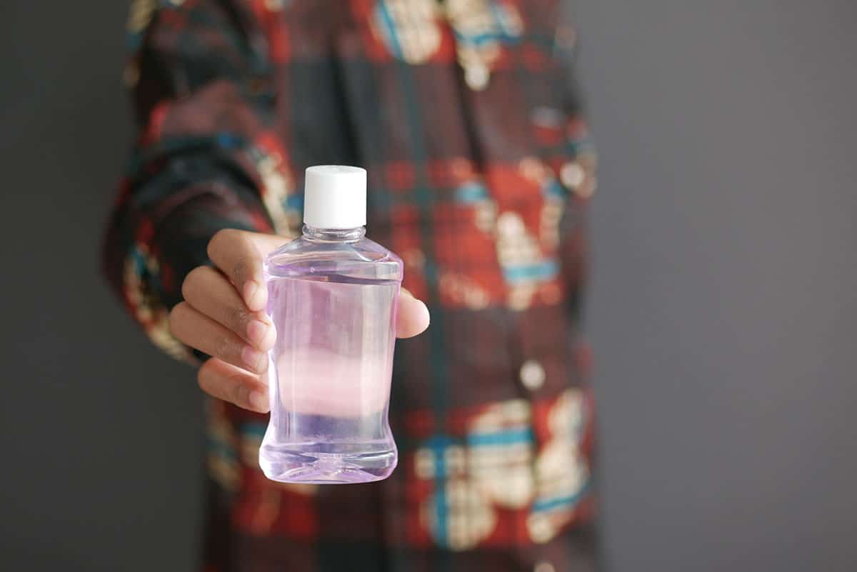 man holds out a generic bottle of dry mouth mouthwash