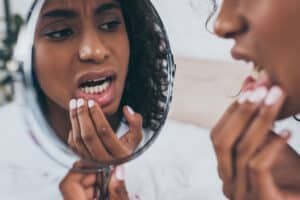 woman looking questioningly at her smile in the mirror for signs of bad dental hygiene