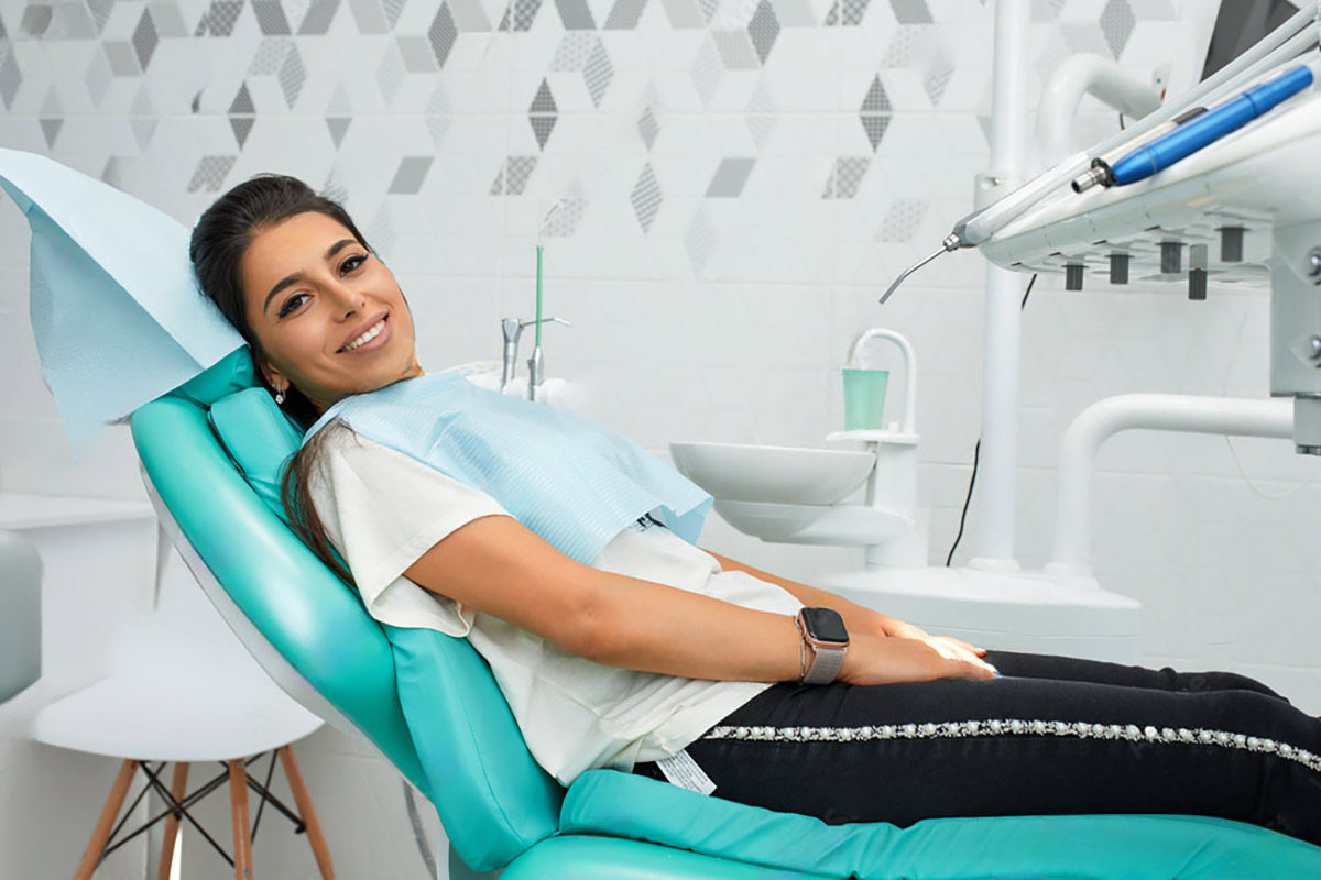 woman lies in the dentist chair smiling at the camera after a successful root canal treatment