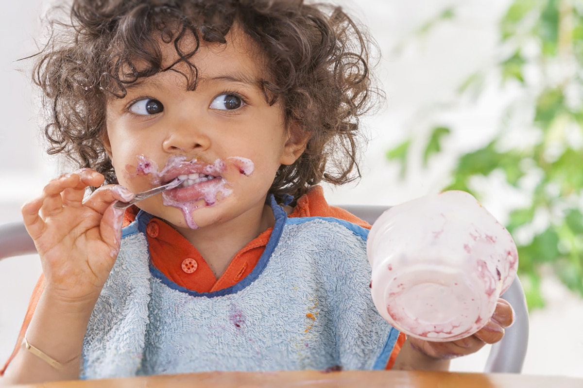 toddler smiling as he chows down on some frozen yogurt