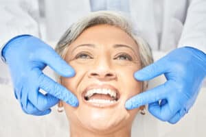 older woman smiling as she receives dental care for elderly denture wearers