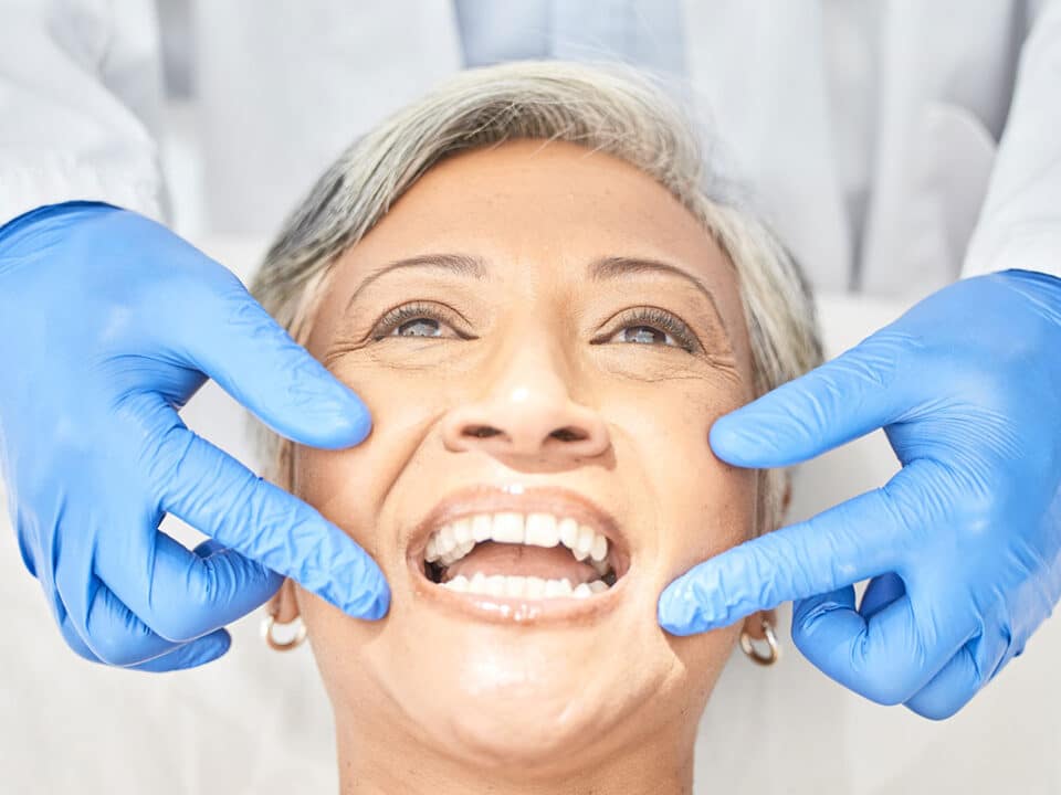 older woman smiling as she receives dental care for elderly denture wearers