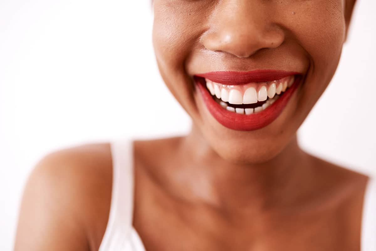 woman with red lipstick smiles showing healthy teeth and gums
