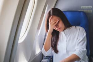 woman on plane looks concerned and is debating if she should get dental work done abroad as part of dental tourism