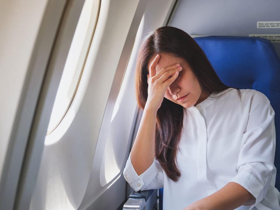 woman on plane looks concerned and is debating if she should get dental work done abroad as part of dental tourism