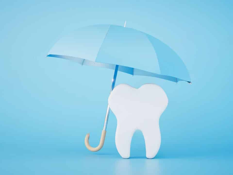 image of a tooth being shielded by a white umbrealla against a blue background to signify how dental guarantees, financing and insurance work in ontario
