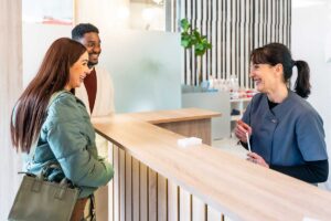 a younger couple is speaking to the receptionist at their hamilton dentist asking about switching from odsp to cdcp coverage.