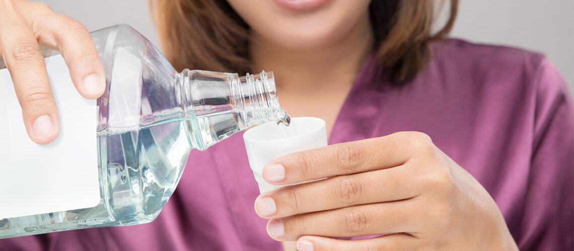 woman pours mouthwash into the cap and explains the 4 benefits of using mouthwash