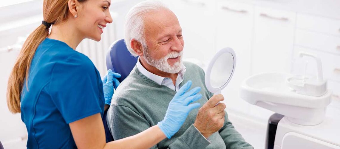 man looking happily at his new smile in the mirror after using our 8 tips to maximize your cdcp benefits article to help him get the most out of his coverage