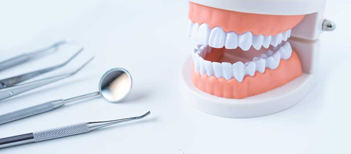 this is the can i remove plaque from my teeth at home featured image showing a set of dentures and some plaque scraping tools