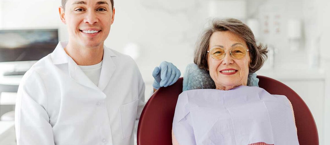 senior woman smiles while sitting beside her dentist after he explained about CDCP eligibility