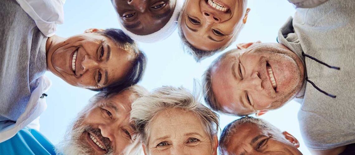 group of seniors putting their heads into a huddle facing the camera from above, celebrating how the cdcp reduces dental health disparities in Canada