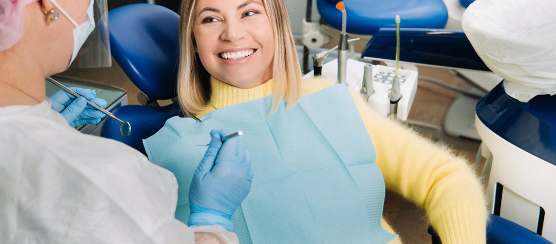 woman in yellow sweater is smiling at her new dentist from the chair