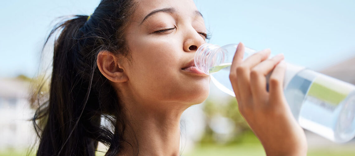 young woman drinking from a bottle of water as one of the many dry mouth solutions and treatments options