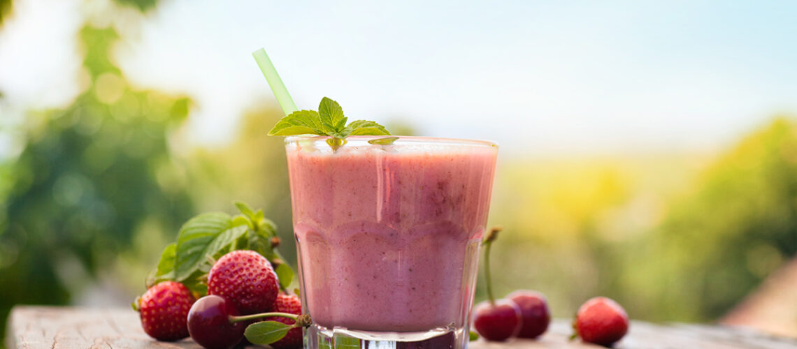 picture of a smoothie in a glass surrounded by berries