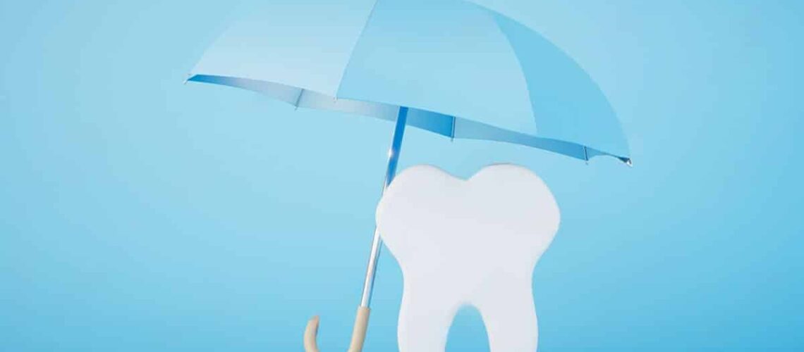 image of a tooth being shielded by a white umbrealla against a blue background to signify how dental guarantees, financing and insurance work in ontario