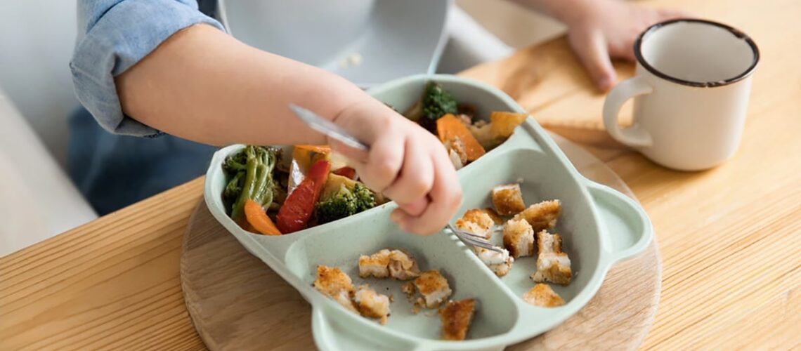 image of a toddler and his plate of nutritious food because his parents know how diet affects dental milestones so they feed him properly