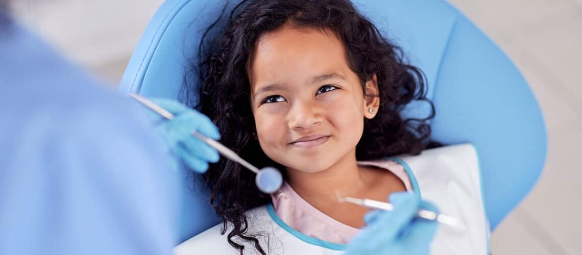 young girl smiling up at her dentist because she knows this is one of the main ways how to prevent cavities in children