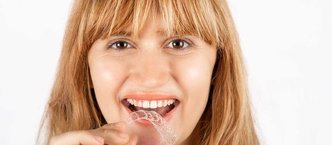 woman with a mouthguard in her hand can tell you how to stop grinding your teeth