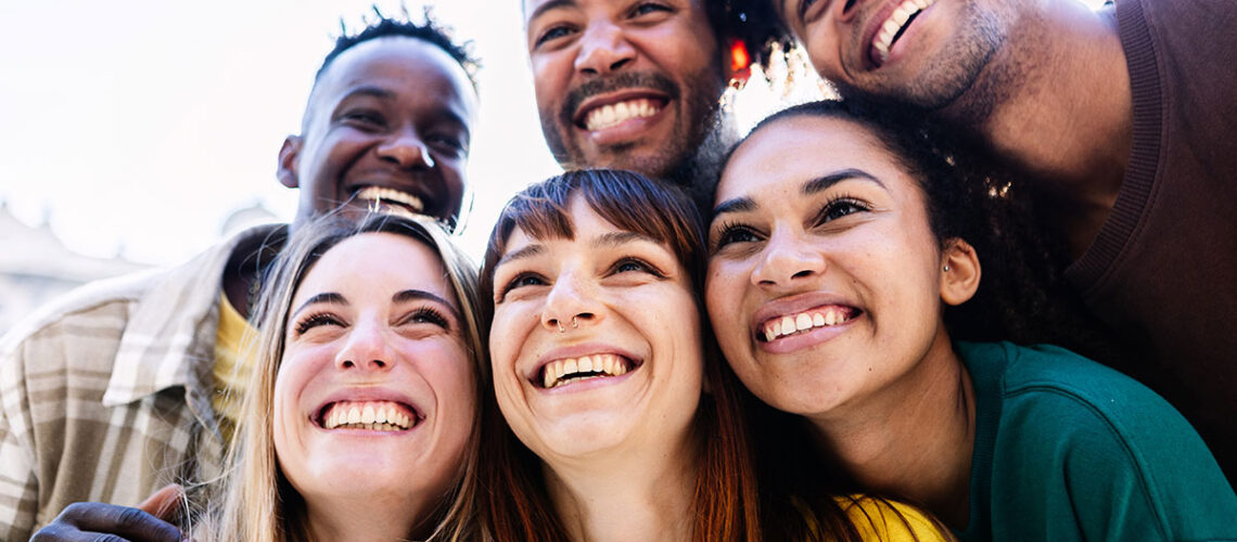 group of young adults clustered together and smiling at the camera. their teeth are perfect so they obviously know about the keys to preventing gum disease