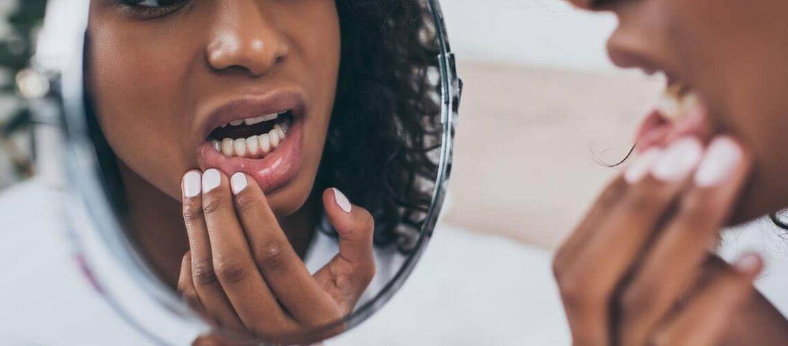 woman looking questioningly at her smile in the mirror for signs of bad dental hygiene
