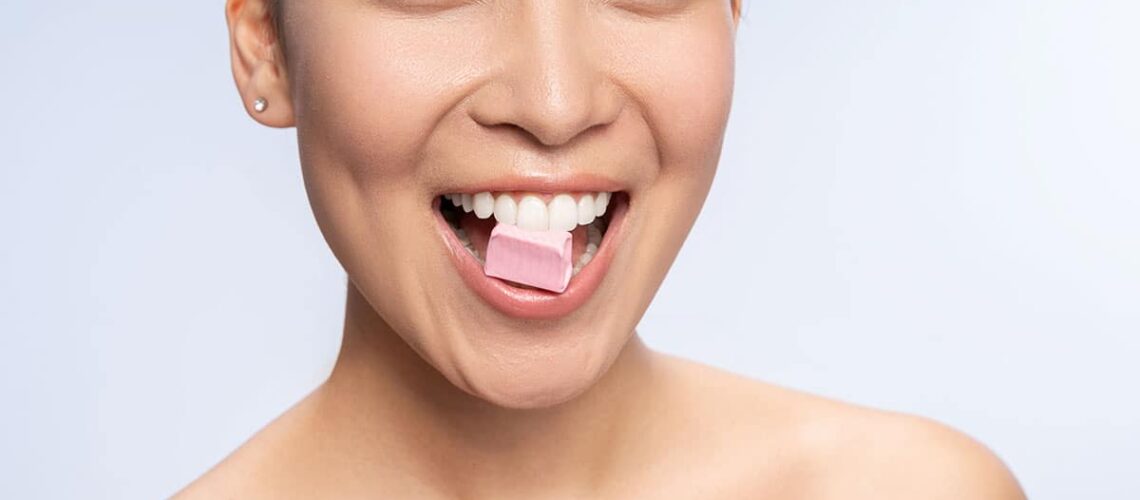 woman enjoys chewing her xylitol gum as a sugar substitute and oral health enhancer