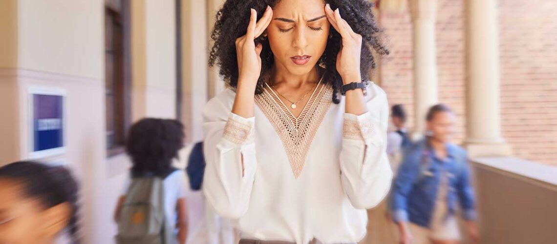 woman holding her hands to her temples and wondering about the impact of stress on oral health