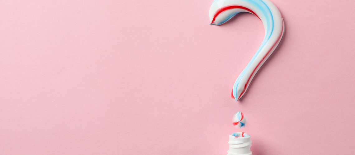 featured image for how to choose the right toothpaste which shows a tube of toothpaste with a question mark spelled out in paste on a pink background
