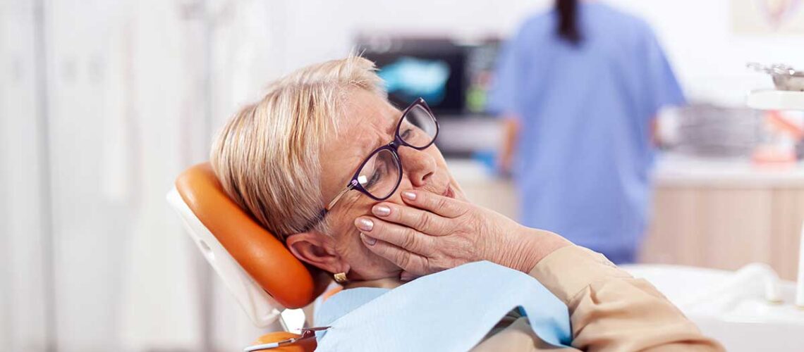 elderly woman holds her face at the dentist and wonders what to do if her cdcp coverage doesn't include her treatment