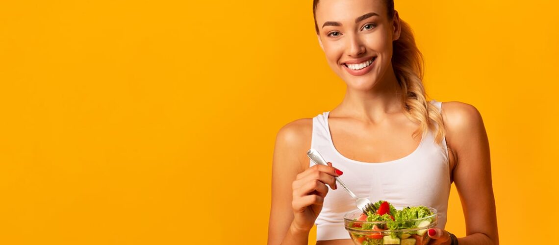 woman knows what to eat for healthy teeth so she has a bowl of salad and a fork in her hand